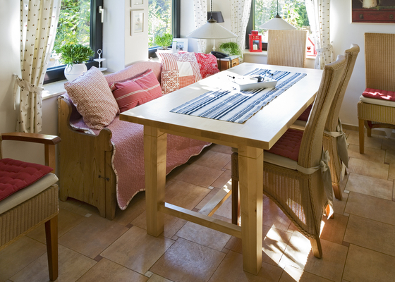 Ein wenig romantisch – Ein moderner Tisch, umstellt mit Rattanstühlen und aufgrund der echten Bauernbank ein wenig romantisch. Close
