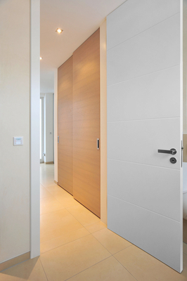 Zimmertüre in Weißlack – … und quer gelegten Alu-Lisenen und modernem Beschlag zum Tür-Öffnen. Garderobe in Nische mit Schiebetüre.